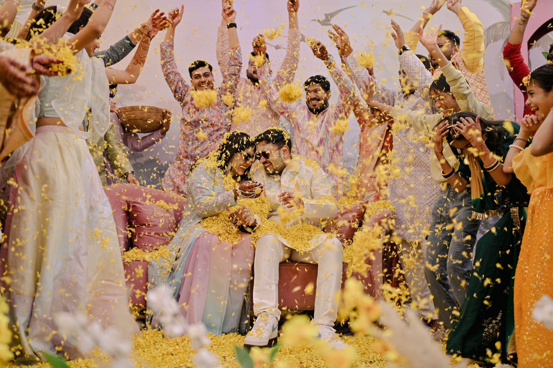 Joyful Indian wedding ceremony with guests showering yellow petals on happy couple.