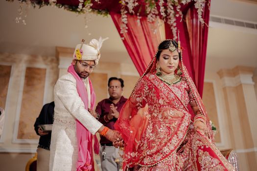 Elegant Indian wedding ceremony featuring bride in red saree and groom in traditional attire.