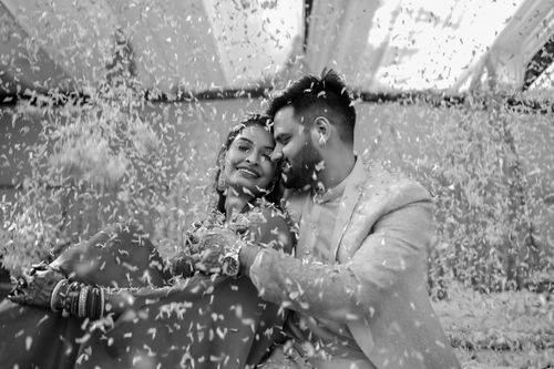 Free A joyous couple embraces amidst falling petals, capturing a special celebration moment. Stock Photo