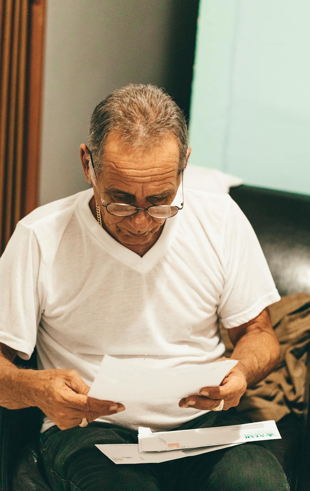 An image showing an old man focused on reading a paper. | Photo: Pexels