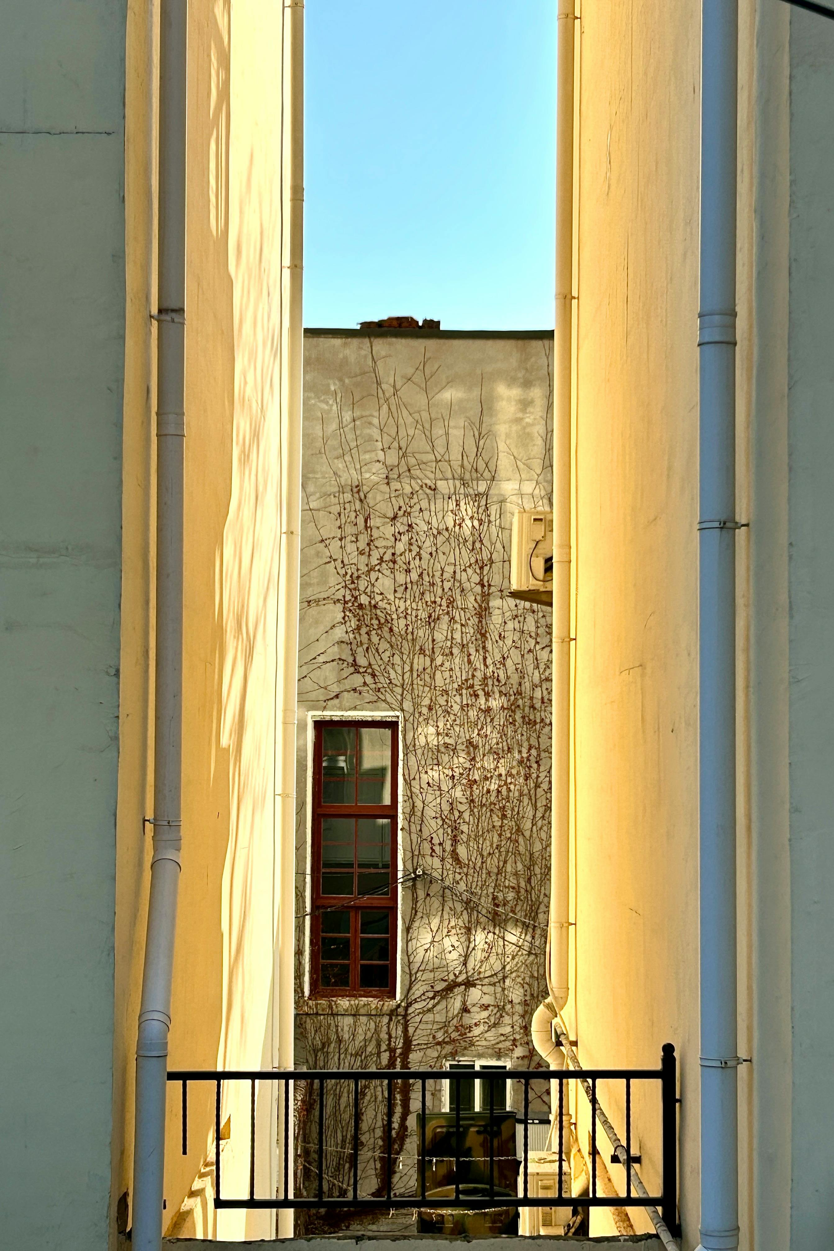 Ücretsiz Sıcak öğleden sonra güneş ışığının vurduğu, doku ve geometriyi ön plana çıkaran, şehir içi bir ara sokağın dingin görüntüsü. Stok Fotoğraflar
