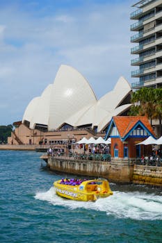 Jet boat speeds past crowded Sydney Opera House on a sunny day.