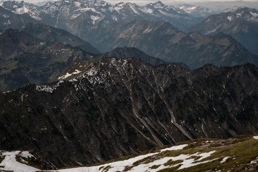 A breathtaking aerial view of rugged, snow-capped mountains under an overcast sky.