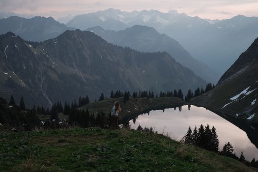 A serene mountain landscape featuring a reflective lake and distant peaks at twilight.