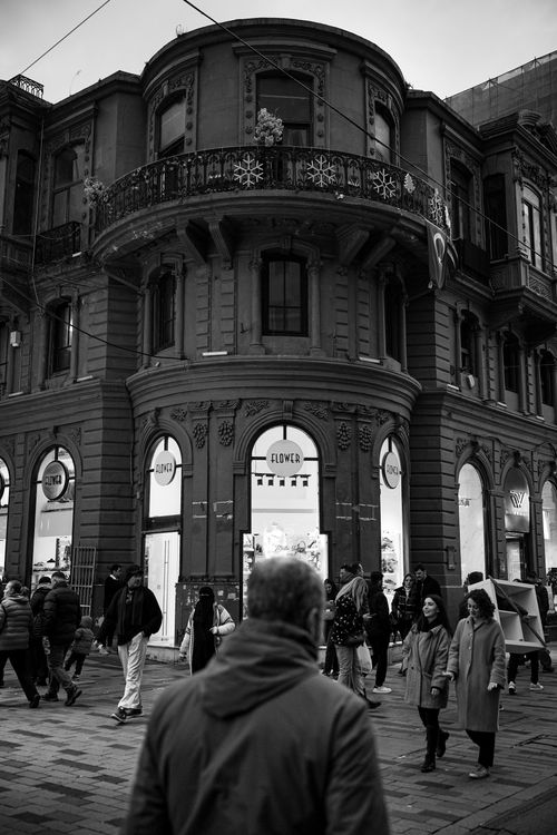 Free Urban street scene with a classic building facade and people walking by, in black and white. Stock Photo