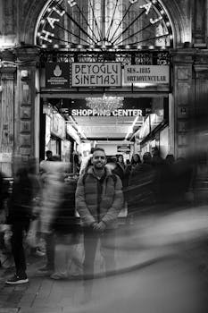 Black and white photo capturing a man at the busy entrance of Beyoğlu Sineması in Istanbul.