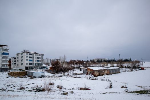 A serene urban scene covered in fresh snow during winter, showcasing residential buildings and open land.