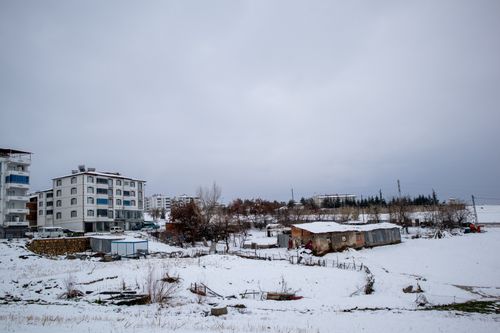 Free A serene urban scene covered in fresh snow during winter, showcasing residential buildings and open land. Stock Photo