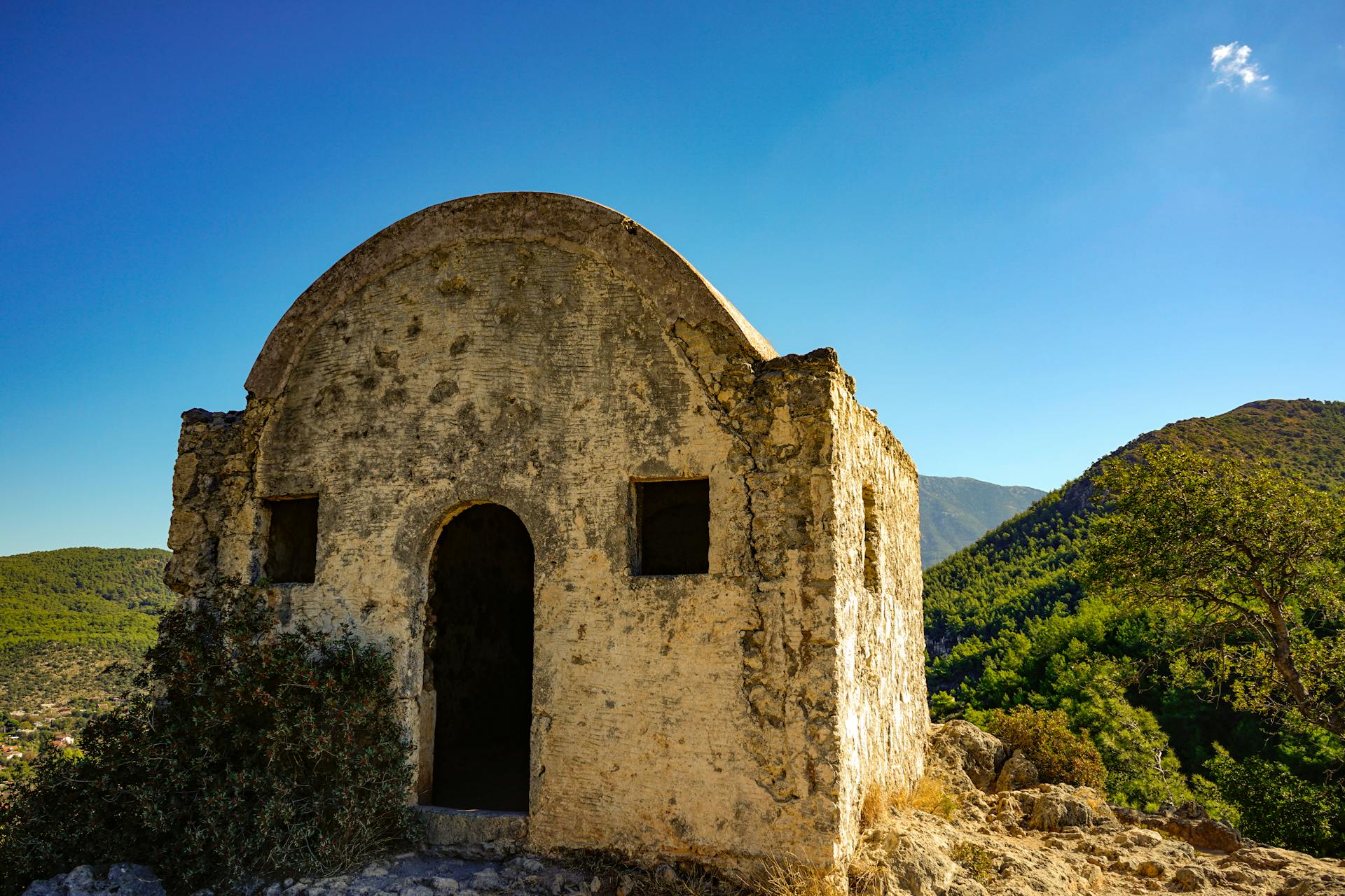 Ancient stone building set against a mountainous landscape in Kayaköy, Türkiye.