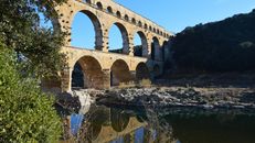 The ancient Roman aqueduct Pont du Gard stands tall over the Gardon River in Occitanie, France.