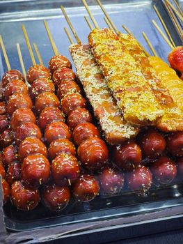 Close-up of assorted candied fruit skewers, perfect for street food enthusiasts.