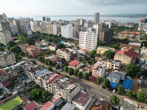 Aerial view of Maputo's urban landscape with buildings and coastline.