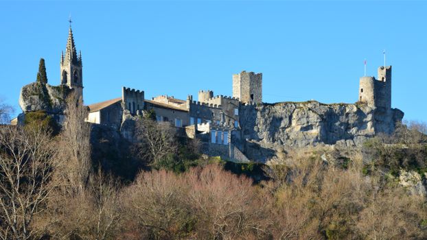 A picturesque view of the medieval castle in Aiguèze, Occitanie, France, set against a clear blue sky.