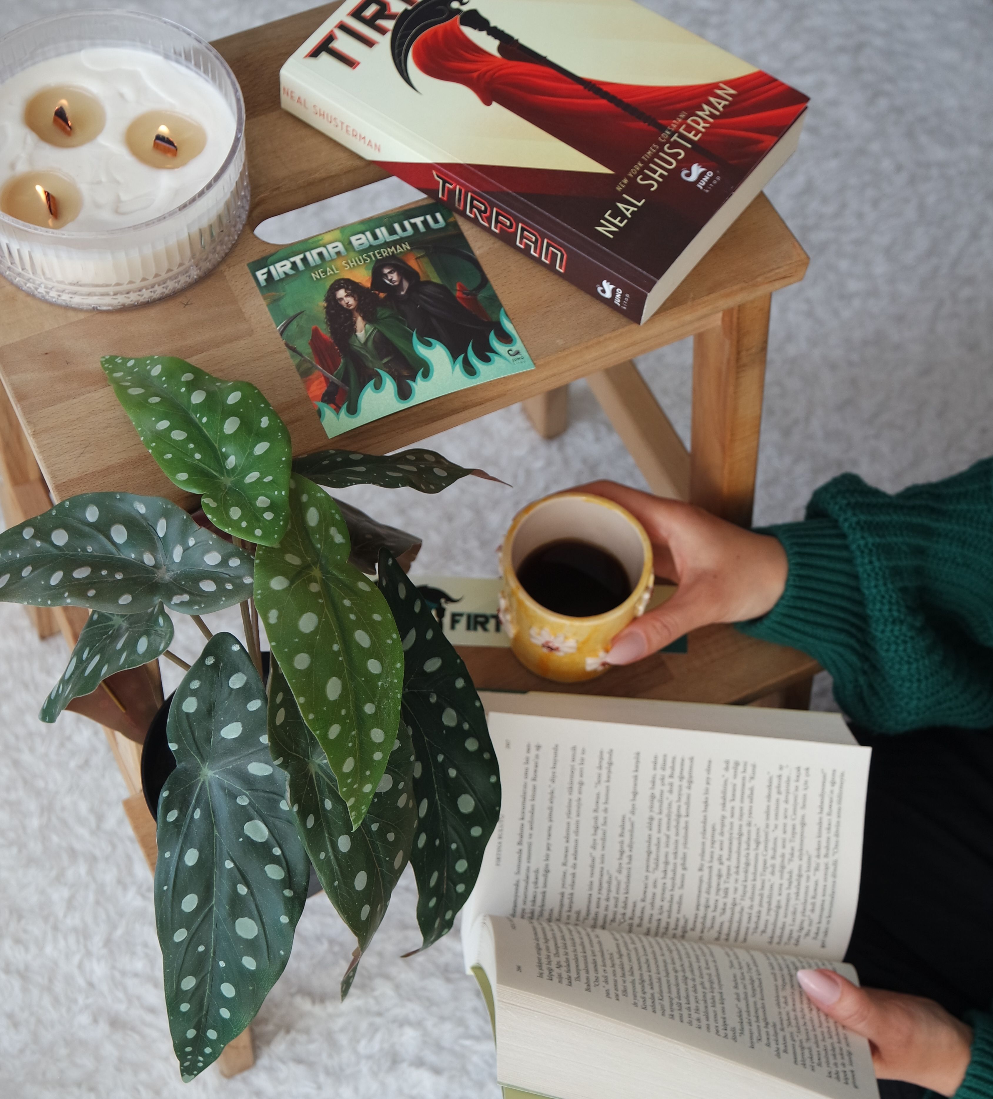 A peaceful reading nook with books, coffee, and a candle on a wooden table.