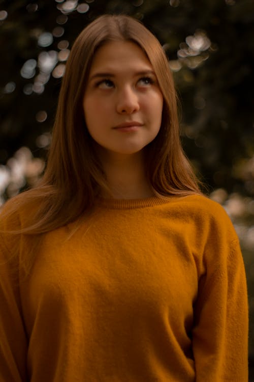 Young Woman in Orange Top With Her Eyes Looking Up