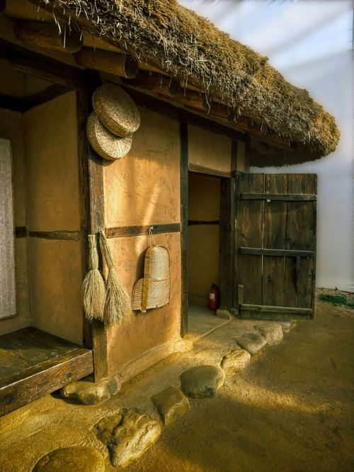 Free Traditional Korean hanok with straw roof and wooden door in Gyeonggi, South Korea, capturing rustic architecture. Stock Photo