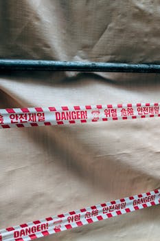 Close-up of red warning tape with multilingual text at a Seoul construction site.