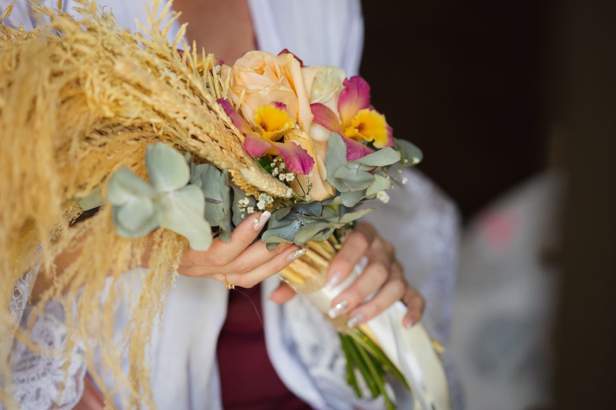 A bridal bouquet of roses, eucalyptus, and pampas grass