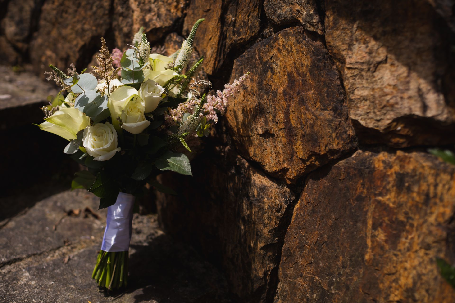 A beautiful bridal bouquet with white roses set against a rustic rock background.