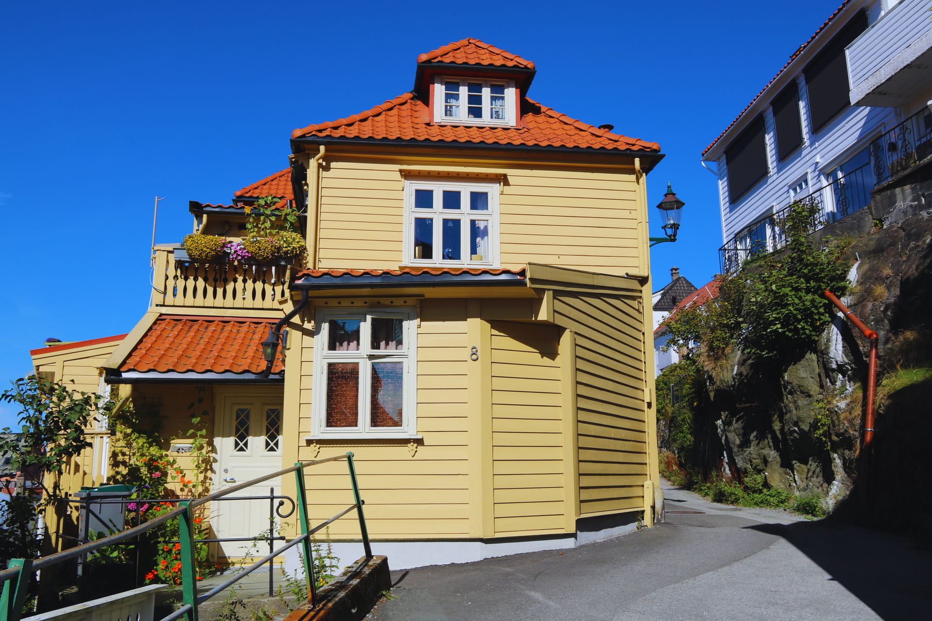 Picturesque yellow house in sunny Bergen, Norway with red roof tiles.