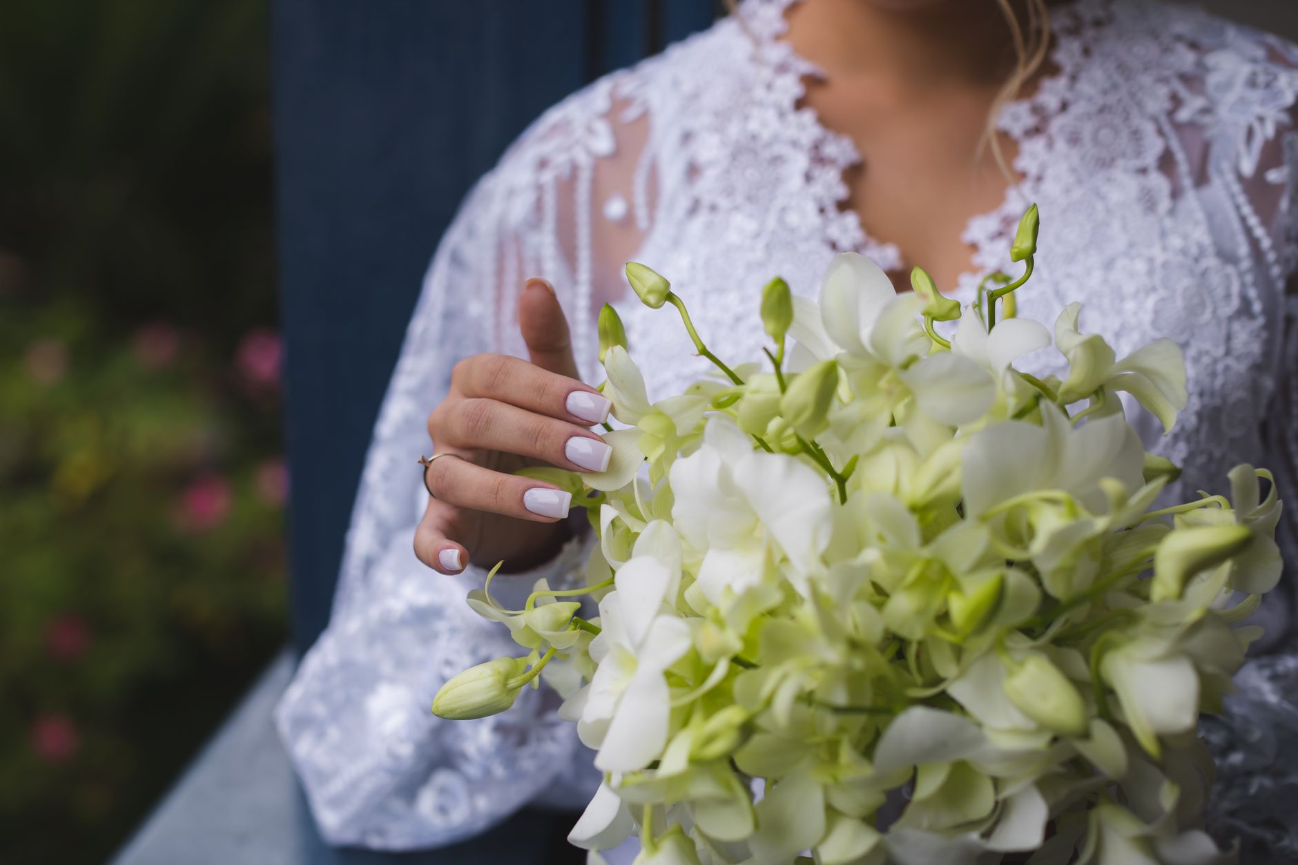 Close-up of bride holding white orchid bouquet, highlighting elegant wedding details.