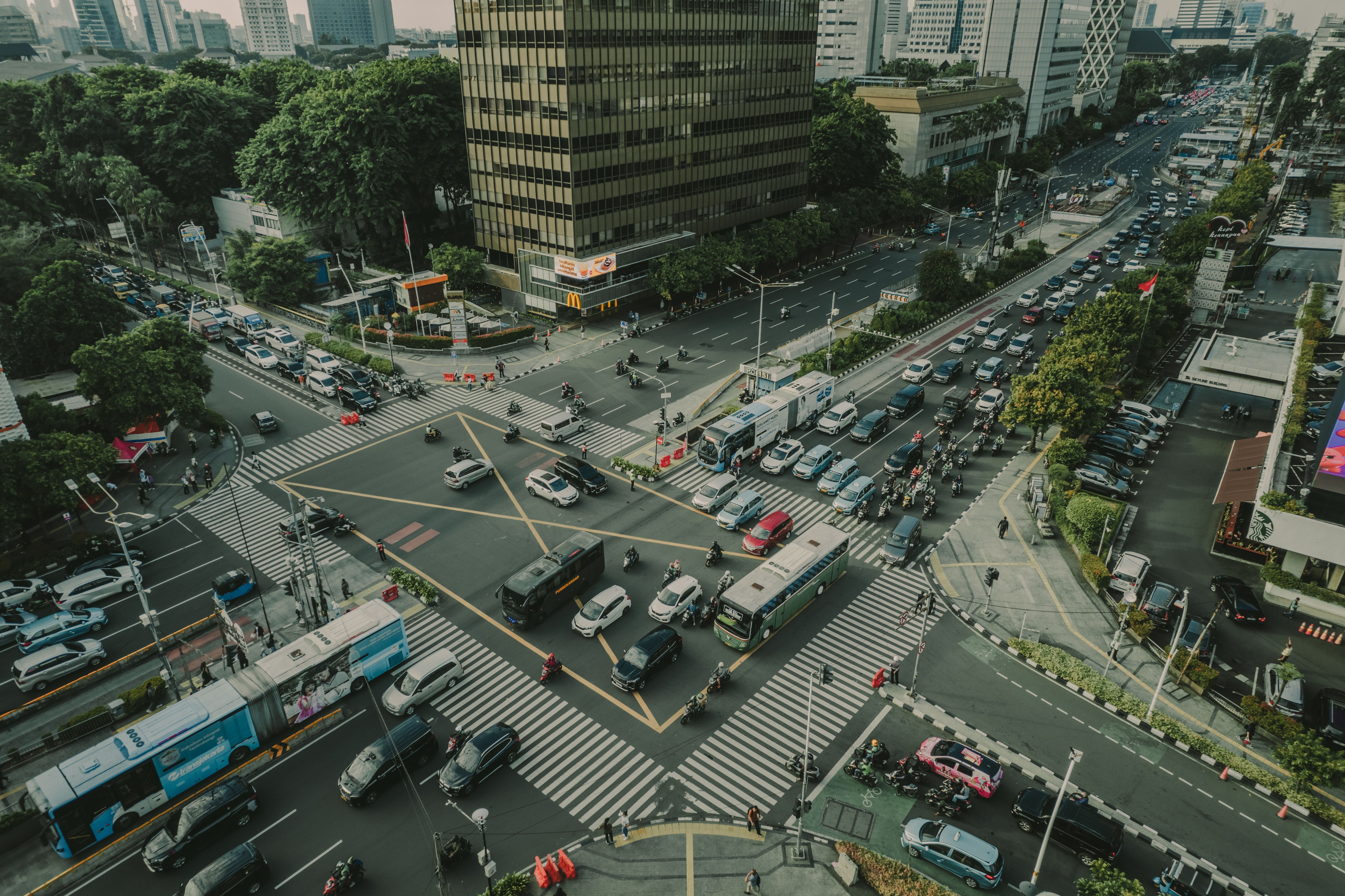 A bustling aerial view of a busy traffic intersection in Jakarta, Indonesia filled with vehicles and pedestrians.