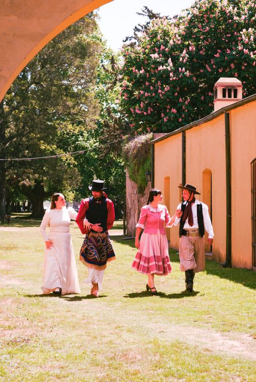 Free Group of four in traditional costumes walking under archway outdoors. Stock Photo