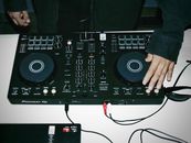 Close-up of DJ mixing on a controller, creating vibrant tunes.