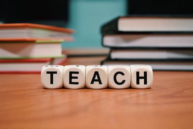 A stack of school books, an apple and alphabet blocks on a desk