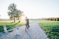 一名骑自行车的人穿过意大利蒙扎一个阳光明媚的公园，周围绿树成荫，天空晴朗