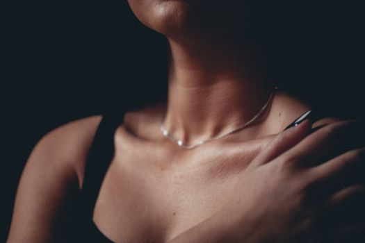 Close-up of a woman's neck wearing a necklace, capturing elegance and fashion in a studio setting.
