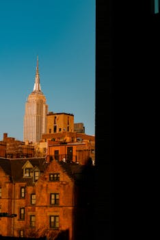 Empire State Building amidst orange-hued buildings. Iconic New York City architecture.