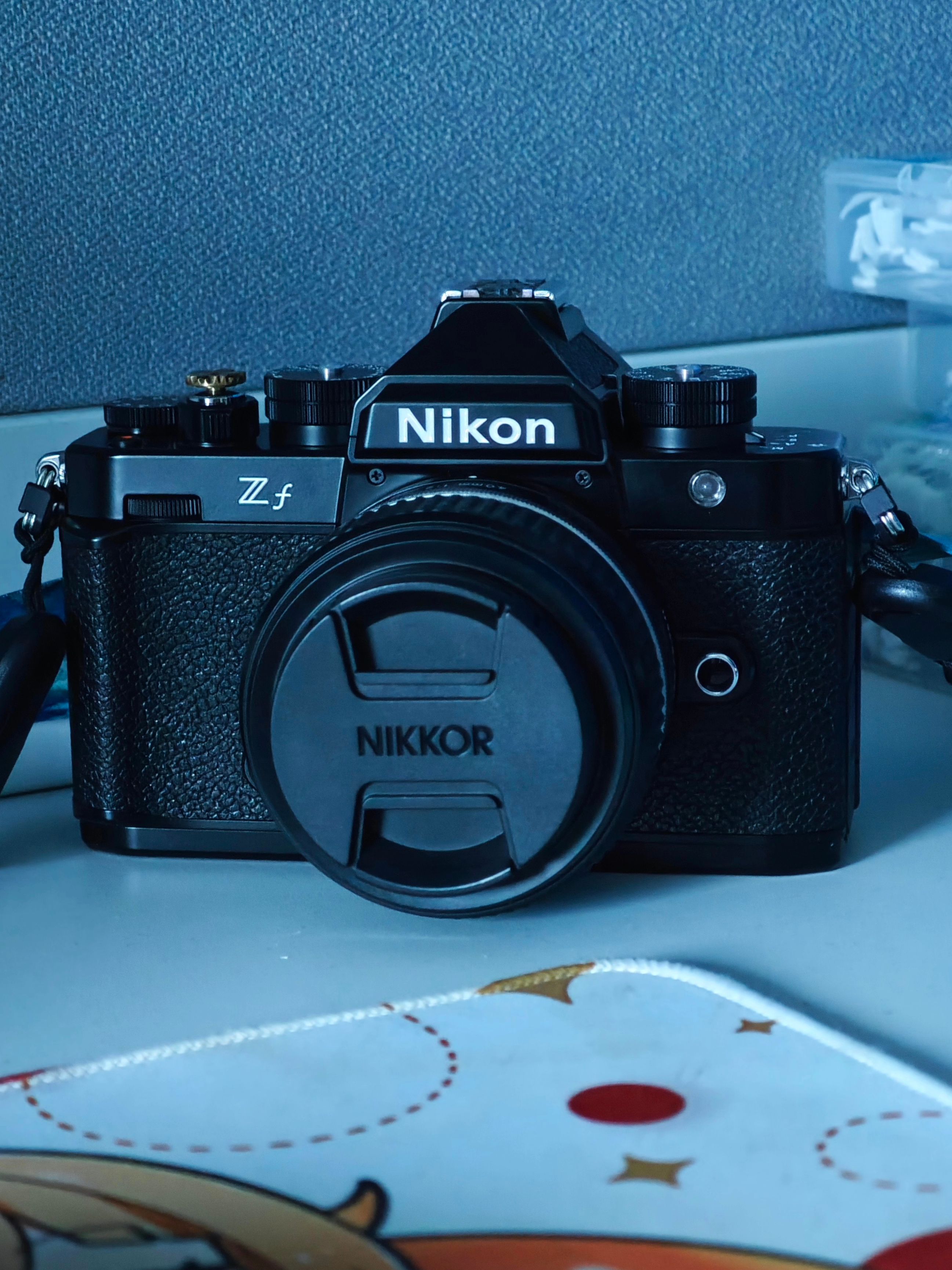 Classic black DSLR camera with lens cap on desk, perfect for vintage photography enthusiasts.