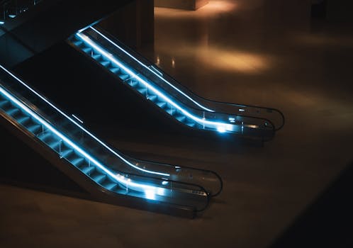 Futuristic escalators illuminated with LED lights in a Paris museum at night.