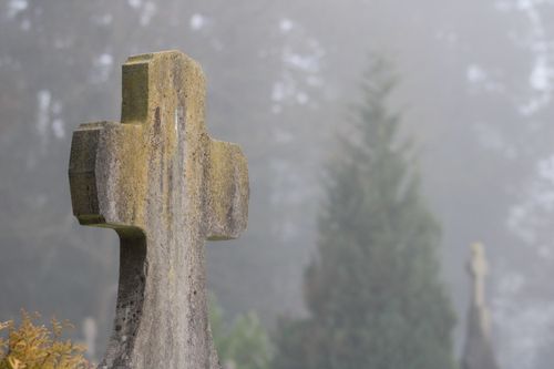 Free Misty cemetery scene with a focus on an aged stone cross, symbolizing tranquility and remembrance. Stock Photo