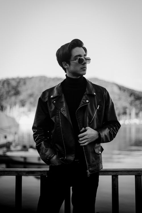 Free A black and white portrait of a man in a leather jacket by the waterfront. Stock Photo
