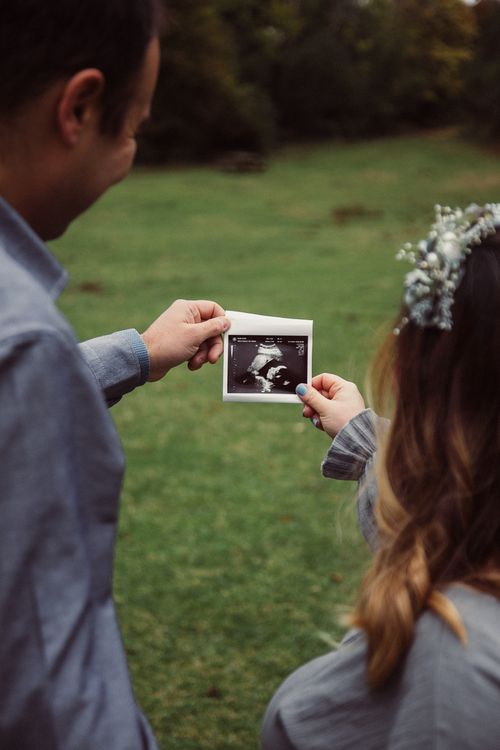 Free A couple holds an ultrasound photo in a serene outdoor setting, focusing on pregnancy. Stock Photo