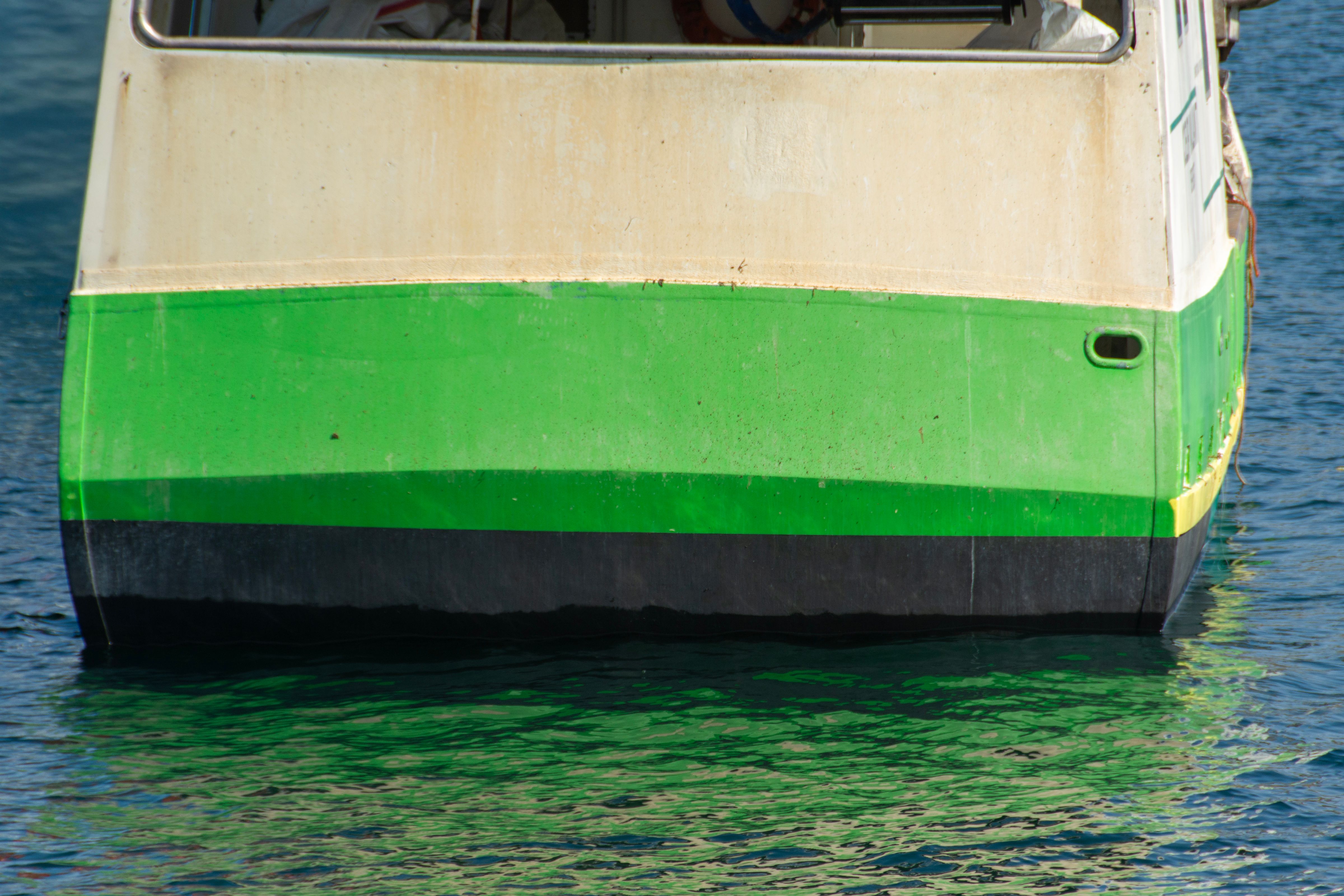 A green boat floating on clear blue water, showcasing a vibrant marine scene.