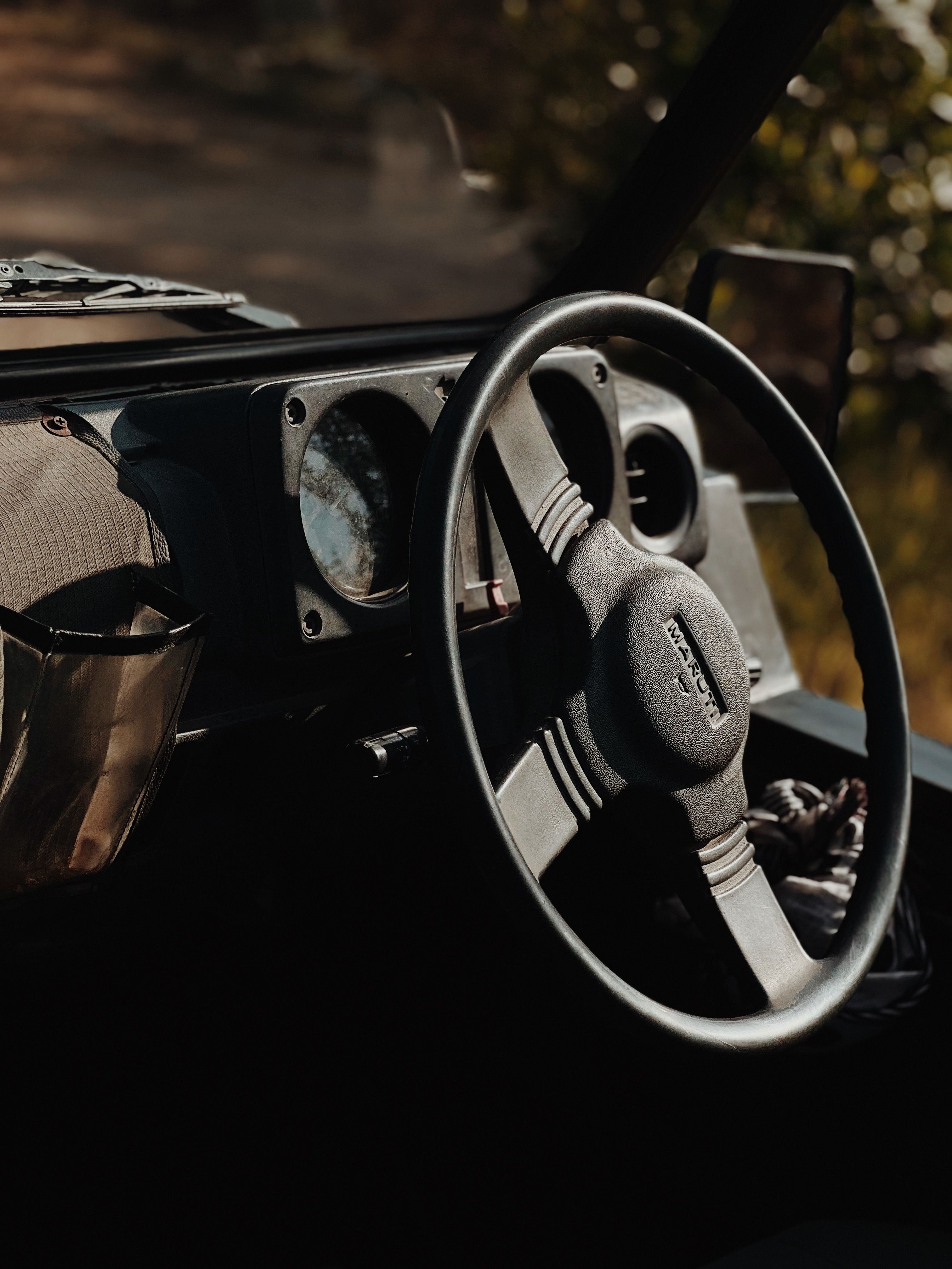 Close-up of a vintage car's steering wheel and dashboard in warm sunlight.