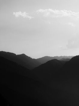Peaceful mountain range silhouette in black and white during daylight.