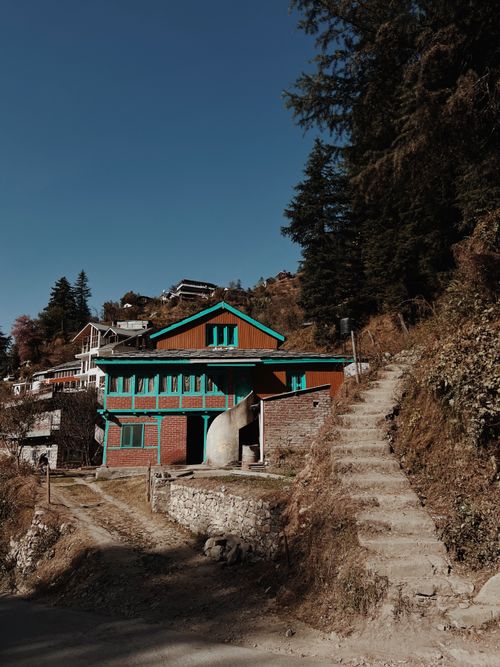 Free A vibrant rural house nestled on a hillside surrounded by trees and stone steps. Stock Photo