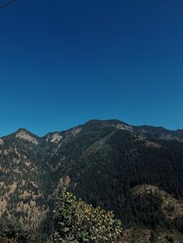 Breathtaking view of a lush mountain range against a clear blue sky, ideal for nature enthusiasts.