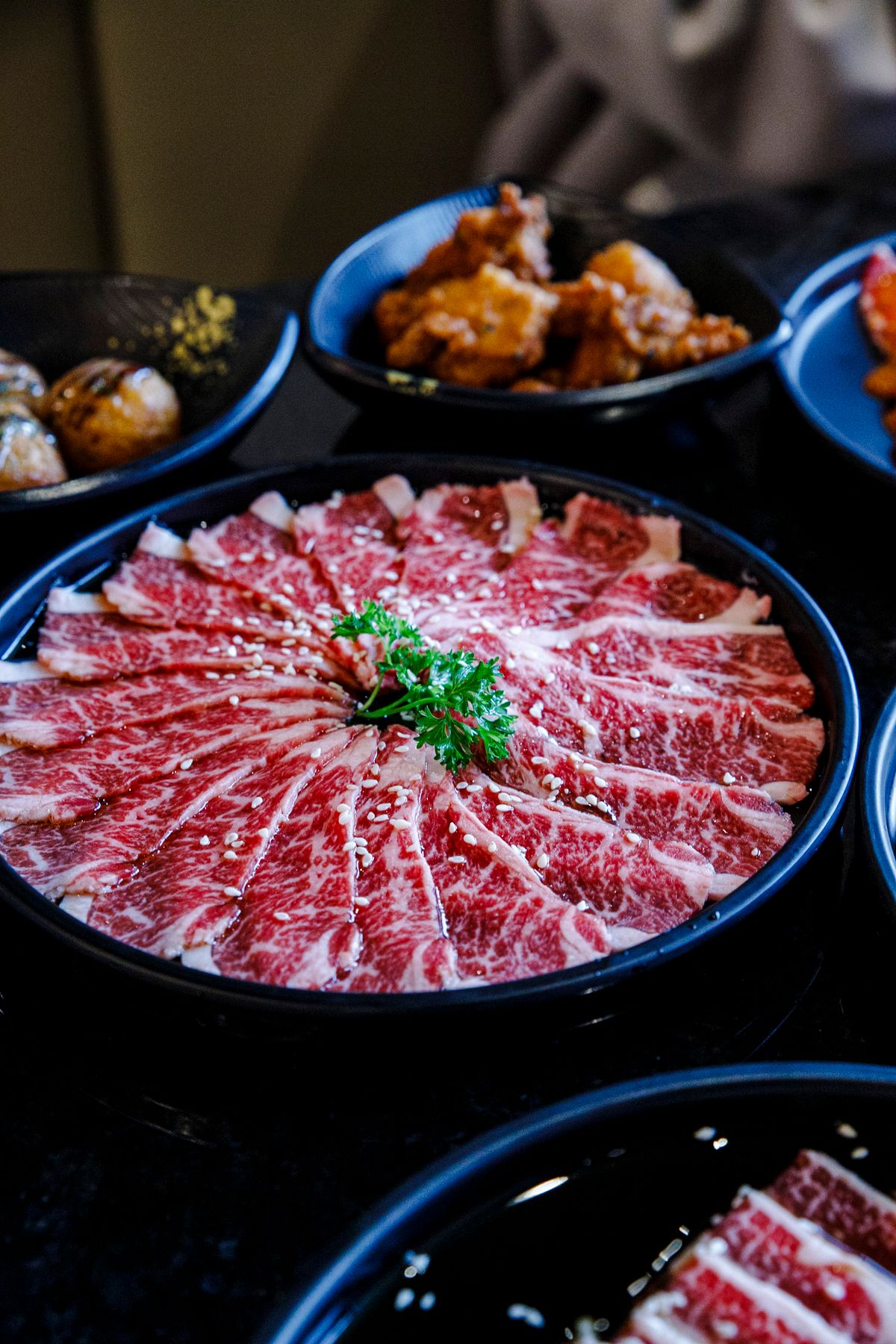 Elegant presentation of thinly sliced wagyu beef with side dishes for sukiyaki or shabu-shabu