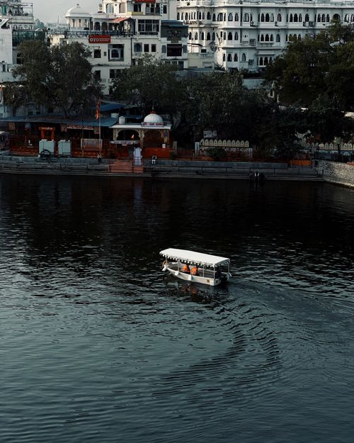 Free White boat navigating city lake surrounded by historic architecture. Stock Photo