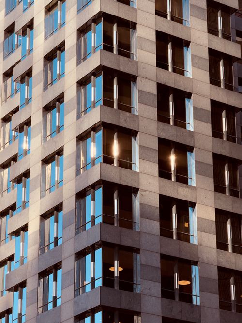 Free Close-up exterior of a modern high-rise building with glass windows reflecting sunlight. Stock Photo