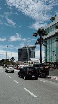 A bustling city street with cars and modern buildings against a blue sky.