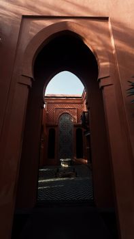 A beautiful Moroccan courtyard with intricate tile designs viewed through an archway.