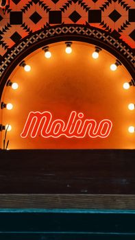 A warm vintage-style neon sign reading 'Molino' with surrounding light bulbs and patterns.