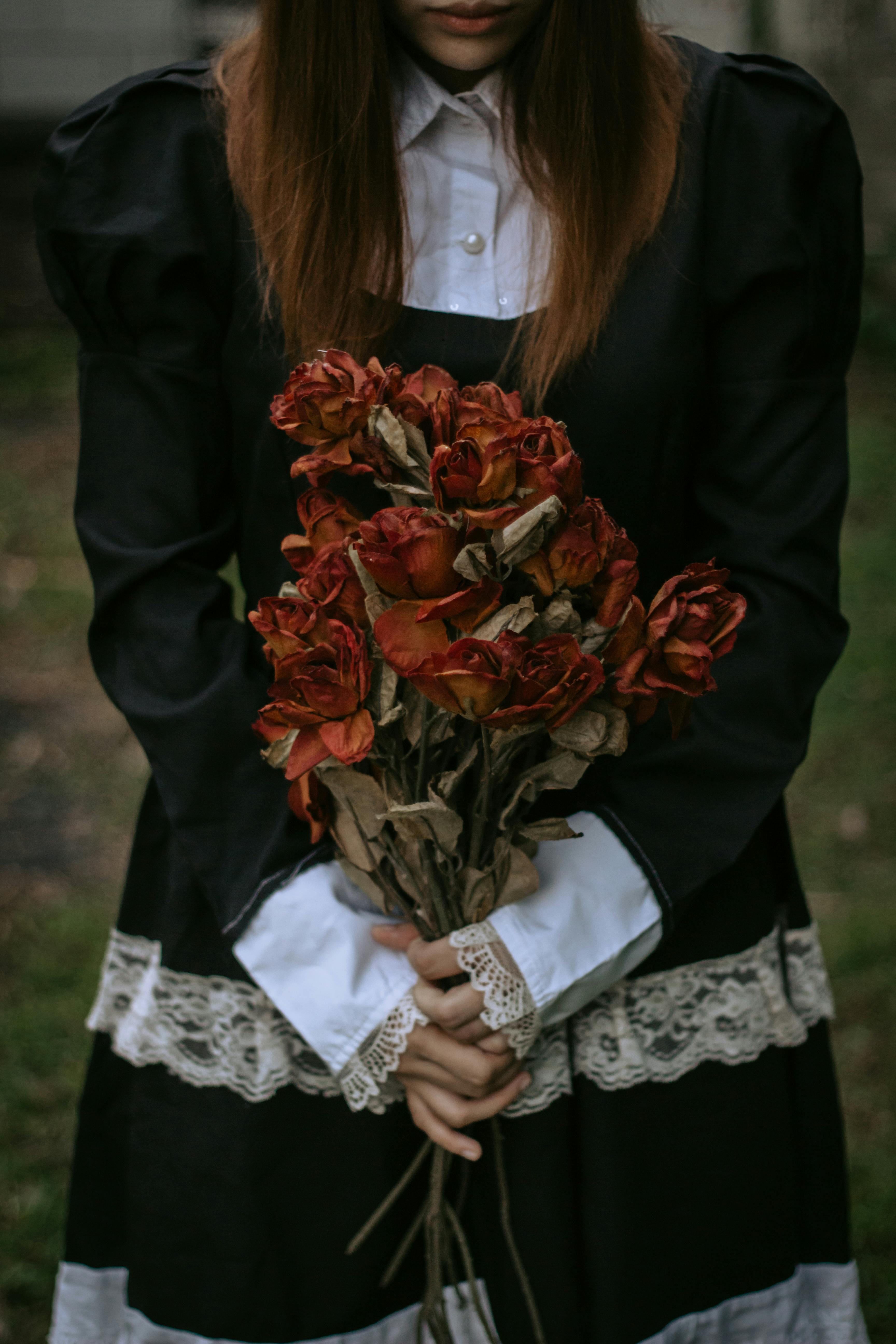 woman in a black dress oddly holding a dry bouquet of roses