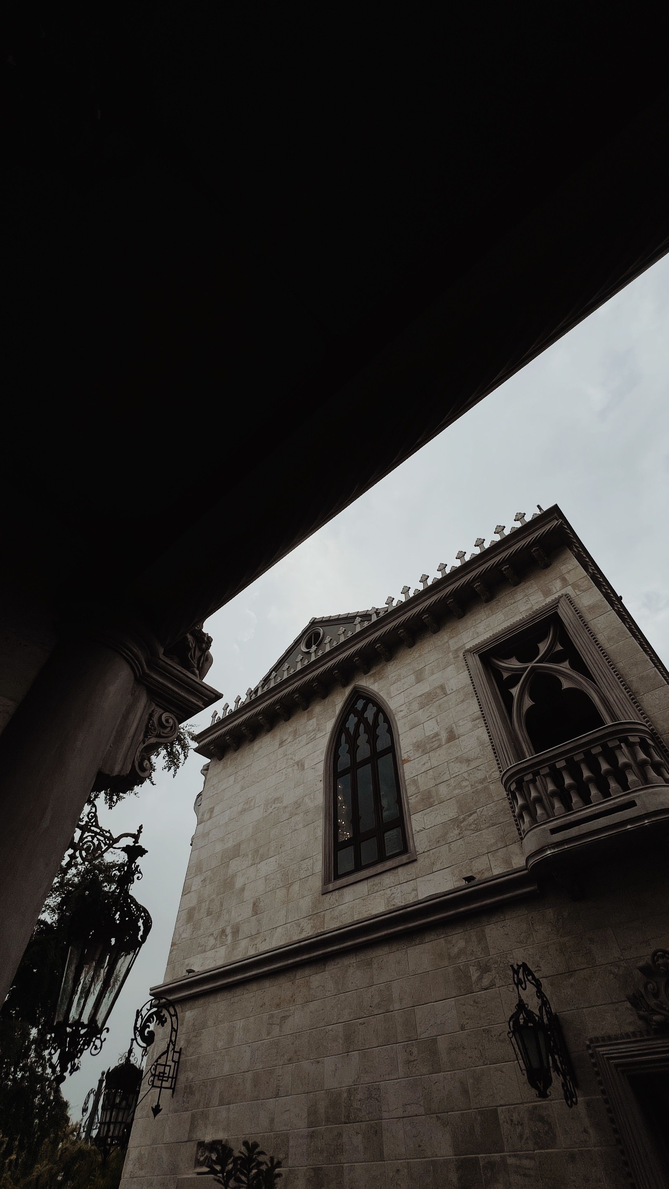 Fotomural Edificio de estilo gótico con ventanas ornamentadas y fachada de piedra contra un cielo nublado.